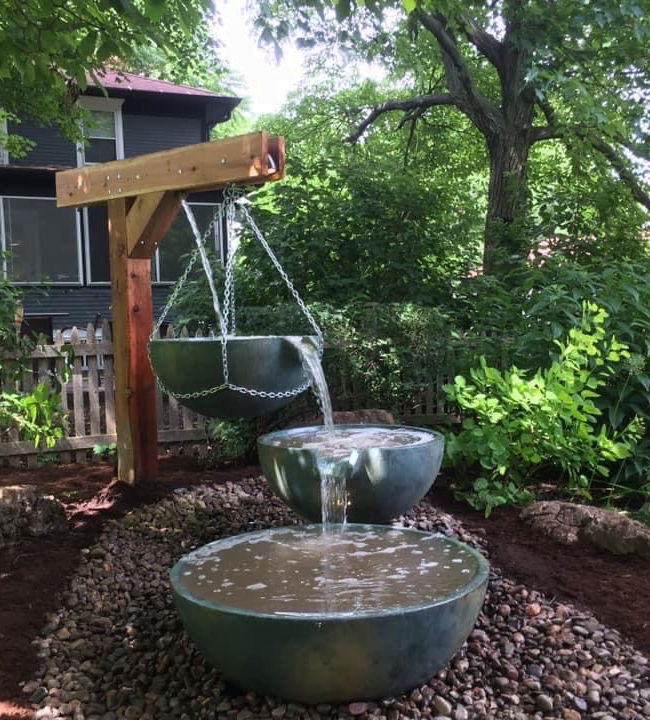 Hanging spillway bowl pouring into a basin bowl under a wood post.