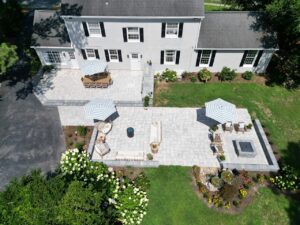 Aerial view of finished paver patios and planting beds behind a white two-story home.