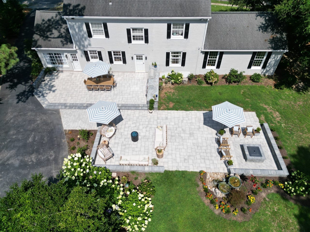 Aerial view of finished paver patios and planting beds behind a white two-story home.