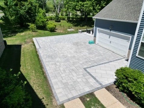 Aerial view of a large gray paver patio beside a garage