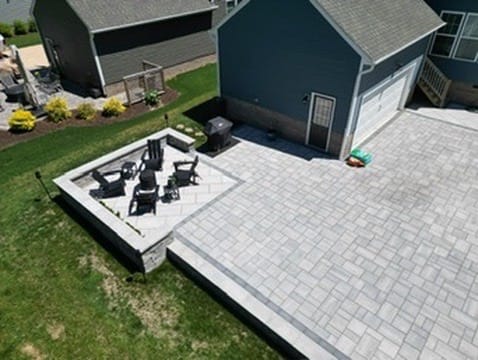 Aerial view of a paver patio with raised seating area and grill