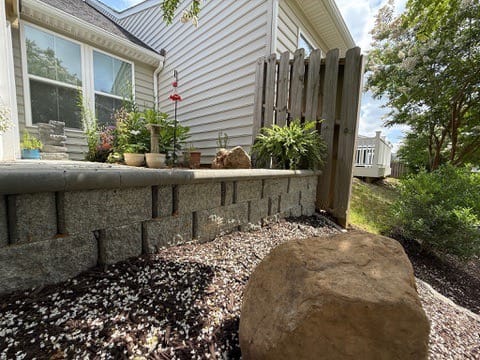 Block patio wall with boulder and mulch bed below