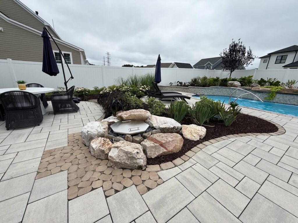 Boulder-ringed fire pit on a paver patio near the pool in Tabb, VA