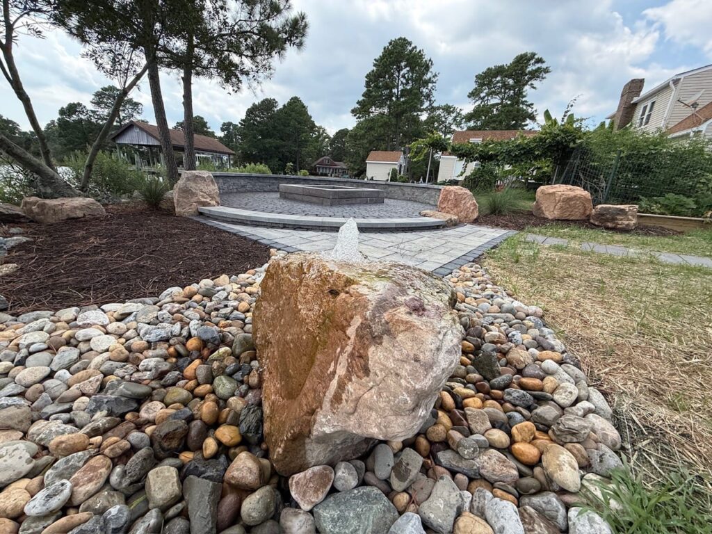 Bubbling rock fountain set in river rock beside a fire pit patio in Poquoson, VA