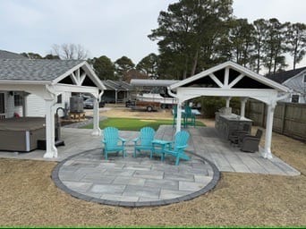Circular paver patio with teal Adirondack chairs in front of pavilions in Poquoson, VA