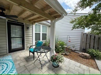 Covered paver patio with bistro set and teal chair