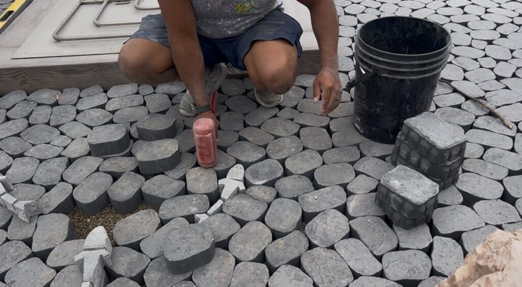 Crew member laying cobble pavers with fish inlays in Poquoson, VA