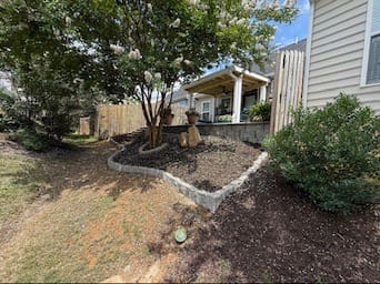 Curved mulch bed with stone edging around a crape myrtle