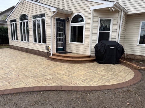 Curved tan paver patio with red border off the back steps