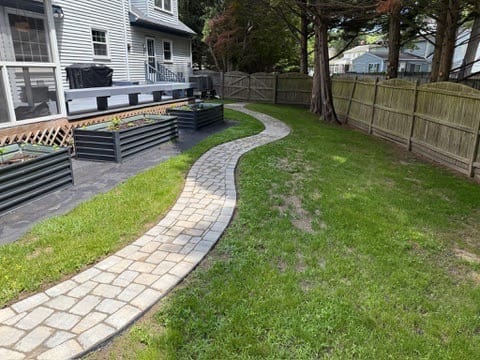 Curving paver garden path through a fenced backyard