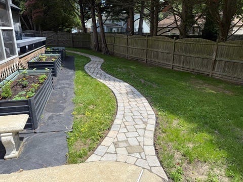 Curving paver path across a lawn beside raised garden beds