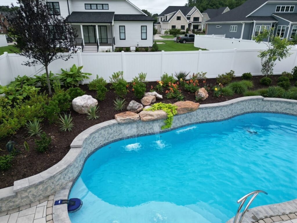 Freeform pool beside a boulder planting bed with flowers in Tabb, VA