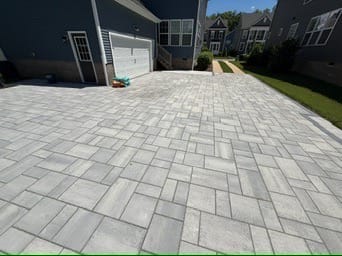 Gray paver patio and walkway leading toward the garage