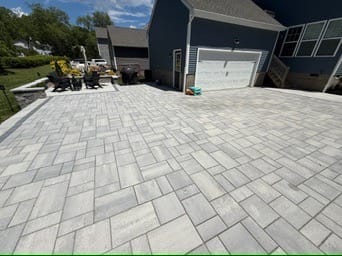 Large gray paver patio leading to a home's garage