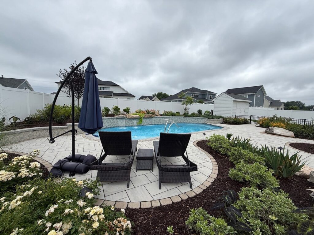 Lounge chairs on a paver pool deck framed by plantings in Tabb, VA