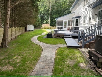 Long paver path along a fence leading to the deck