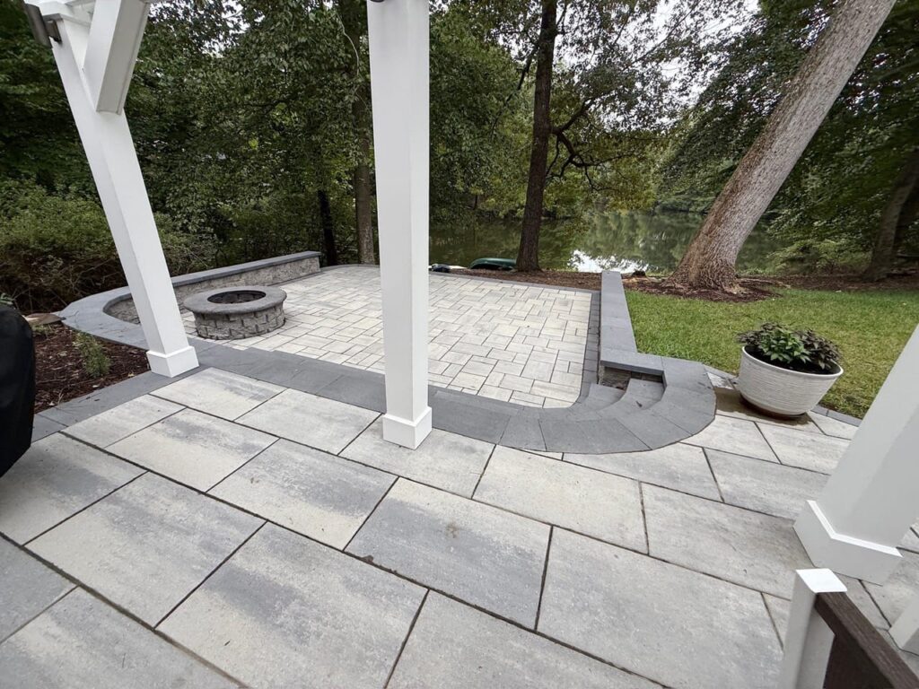 Paver patio with seat wall and fire pit seen from the pergola