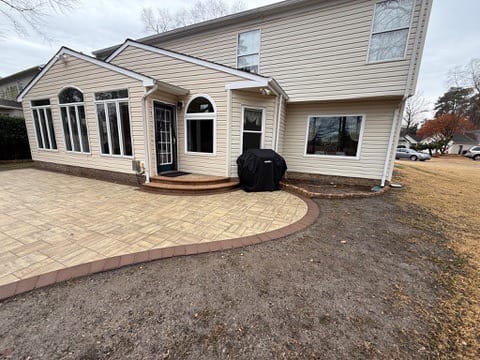 Paver patio with back steps behind a two-story home
