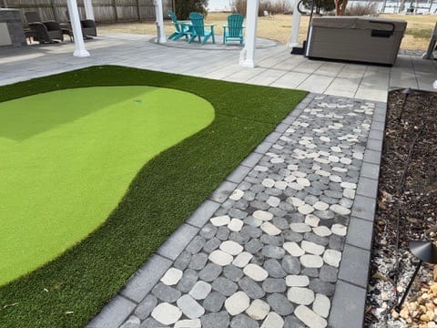 Putting green beside a cobble paver path and gray paver patio in Poquoson, VA
