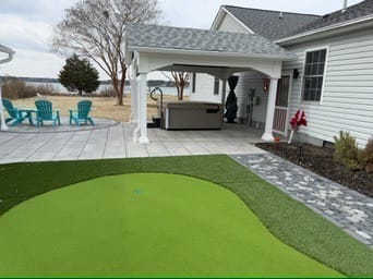 Putting green in front of a white pavilion with hot tub in Poquoson, VA