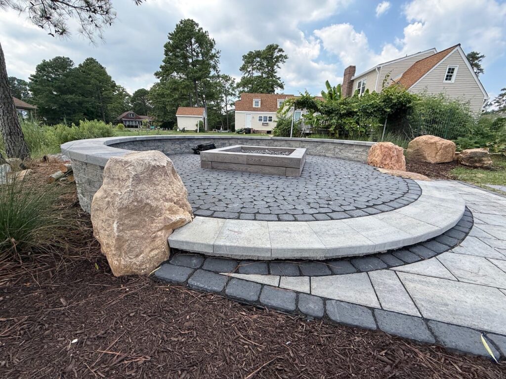 Raised circular paver fire pit patio edged with boulders in Poquoson, VA