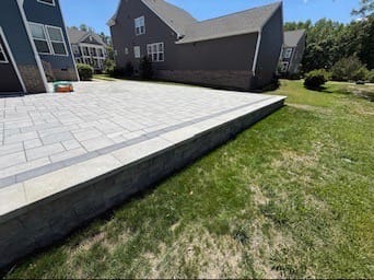 Raised paver patio with stone retaining wall edge