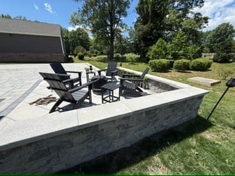 Raised paver seating area with seat wall and black Adirondack chairs