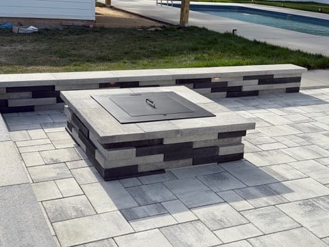 Square paver fire pit with metal cover and two-tone seating wall