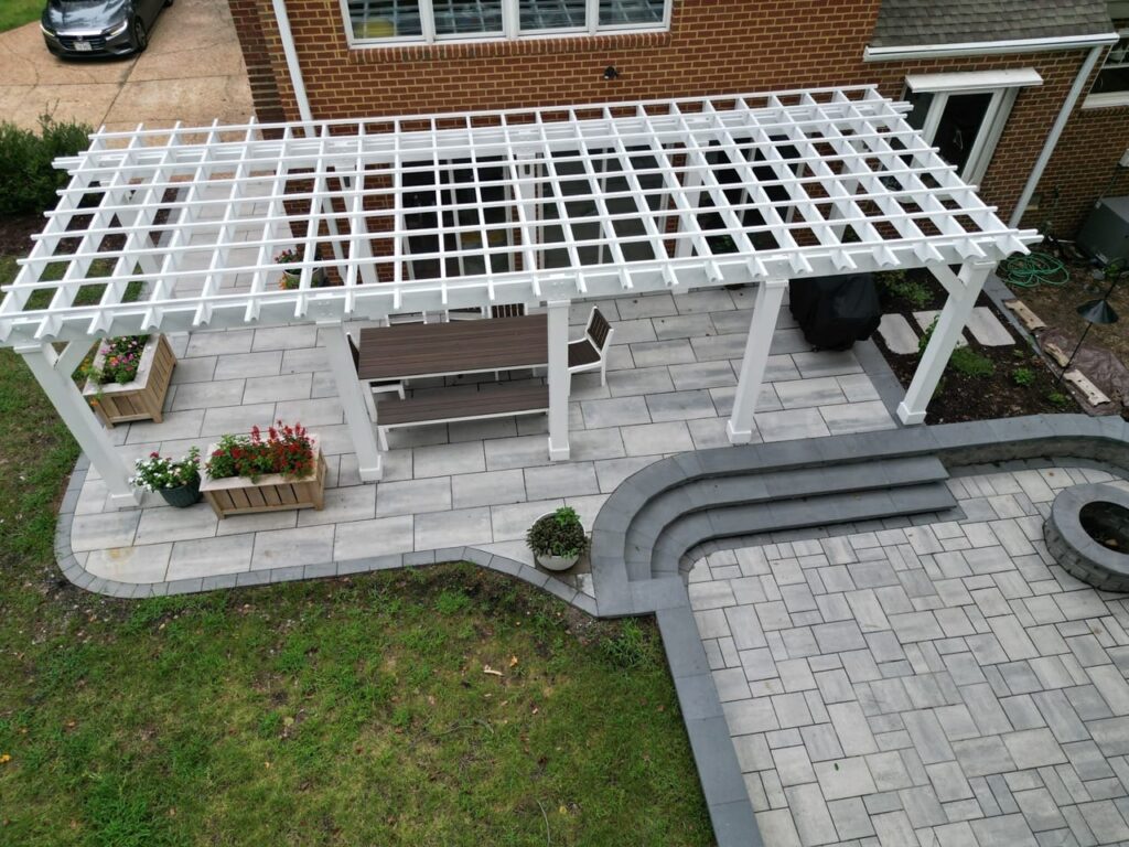 White pergola over a paver patio with curved steps to a fire pit