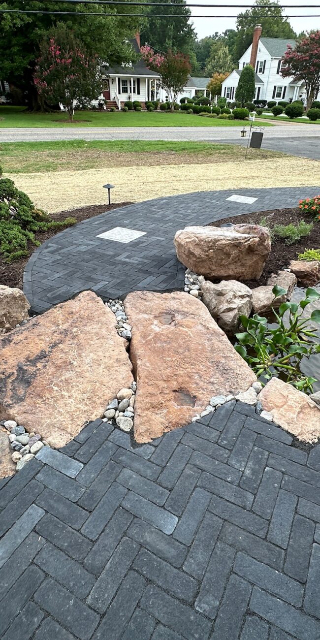Herringbone paver walkway crossing a boulder stream with an urn fountain in Poquoson, VA