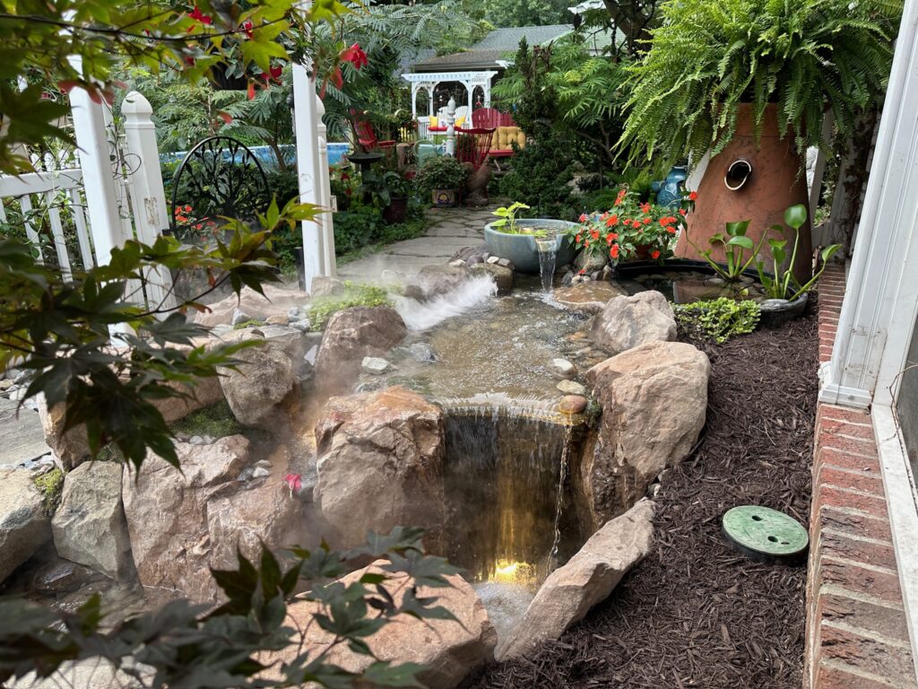 Small waterfall spilling into a pond framed by boulders and ferns in Poquoson, VA