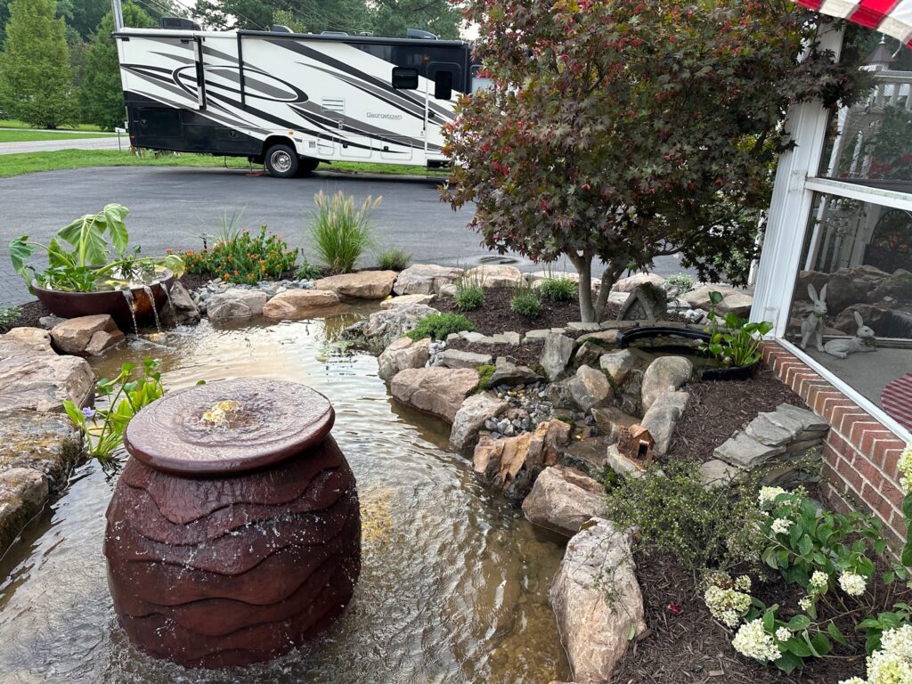 Brown urn fountain bubbling into a boulder-framed pond in Poquoson, VA